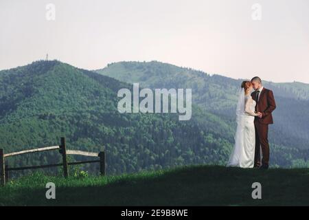 Happy stilvolle Braut und Bräutigam laufen und Spaß in den Bergen am sonnigen Sommertag. Wunderschöne neuvermählte Paar lachen, wahre Gefühle. Emotional rom Stockfoto
