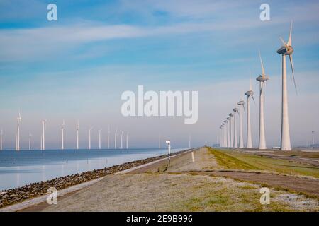 Offshore Windmill Park mit stürmischen Wolken und einem blauen Himmel, Windmill Park im Meer. Niederlande . Europa, Windkraftanlagen im Meer mit blauem Himmel, grünes Energiekonzept Stockfoto