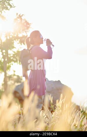 Frau Trinkwasser aus wiederverwendbarer Flasche während des Wanderns Stockfoto