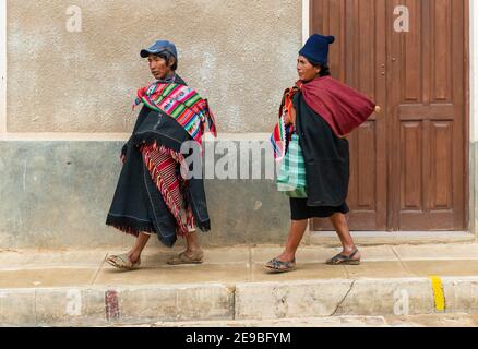 Zwei bolivianische Tarabuco indigenen in traditioneller Kleidung zu Fuß in einer Straße mit kolonialer Architektur in der Nähe von Sucre Stadt, Tarabuco, Bolivien. Stockfoto