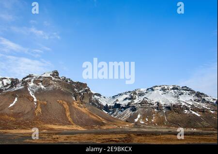 Isländische Tundra-Landschaft, Skaftafell-Nationalpark mit schneebedeckter Bergkulisse und blauem Wolkenhimmel Stockfoto