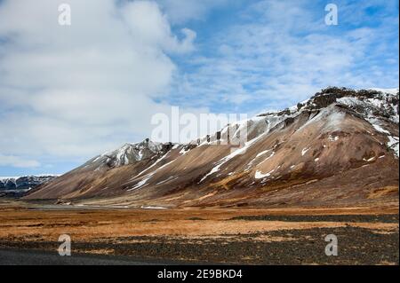 Isländische Tundra-Landschaft, Skaftafell-Nationalpark mit schneebedeckter Bergkulisse und blauem Wolkenhimmel Stockfoto