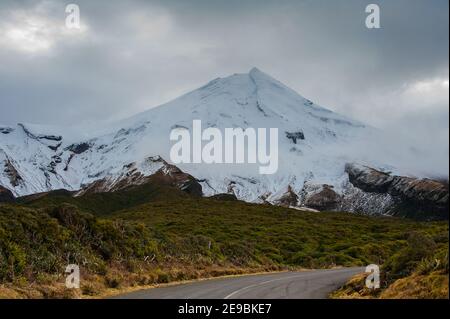 Mount Taranaki (Mount Egmont), Egmont National Park, Neuseeland. Schneebedeckter Gipfel, dunkler stürmischer Himmel in der Dämmerung. Stockfoto