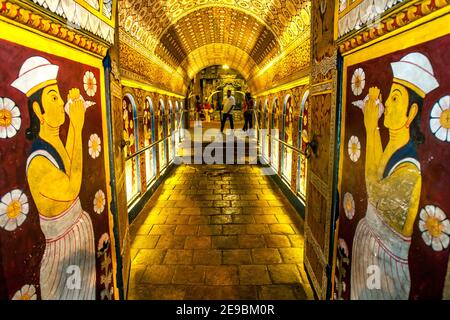 Besucher des Buddhistischen Tempels der Heiligen Zahnreliquie in Kandy in Sri Lanka passieren Ambarawa, einen Tunnel förmigen Flur. Stockfoto