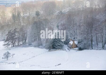 Cotswold Ferienhaus im Schnee am Rande eines Waldes. Lower Coscombe, Cotswolds, Gloucestershire, England Stockfoto