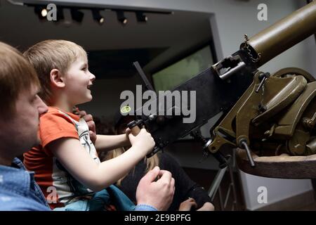 Kind spielt mit Maschinengewehr im Museum Stockfoto