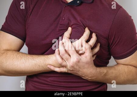 Der Mensch hält seine Hände im Bereich des Herzens. Konzept zum Thema Herzinfarkt und Gesundheitsprobleme. Stockfoto