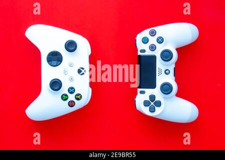 Calgary, Alberta. Kanada. Februar 3 2021. Eine Xbox-Fernbedienung mit Blick auf eine Playstation auf einem roten Hintergrund. Stockfoto