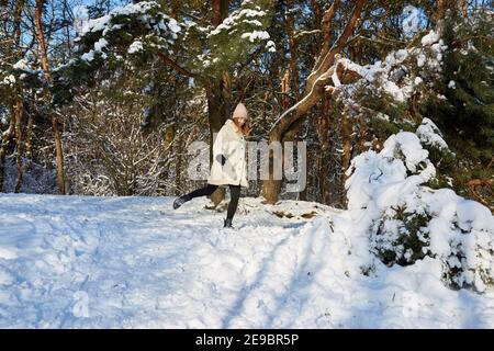 Eine junge Frau, die in einem verschneiten Wald unter einem Gebrochener Kiefernzweig Stockfoto