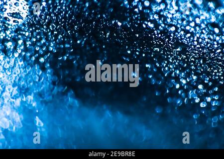 Blauer Wassertropfen Hintergrund. Wassertropfen auf einem Autoglas-Hintergrund. Wassertropfen auf Auto Glas blau Bokeh Hintergrund. Stockfoto