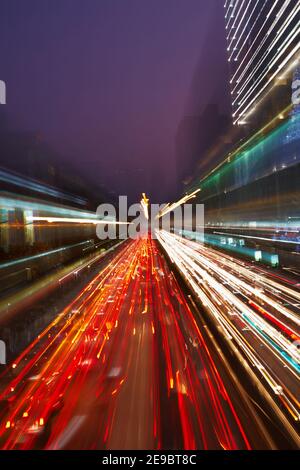 Nachtverkehr in der Stadt, Autoscheinwerfer in Bewegung verschwimmen mit Zoom-Effekt Stockfoto