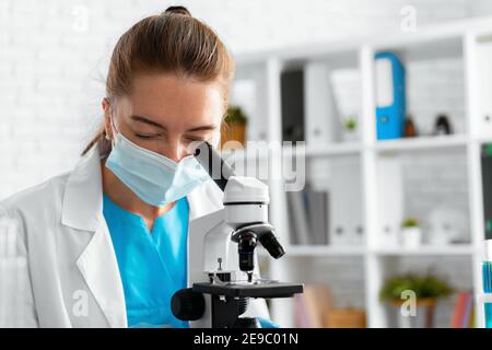 Junge Wissenschaftlerin mit Mikroskop im Labor Stockfoto