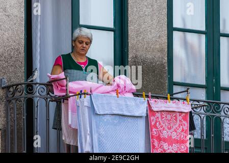 Porto, Portugal - 06. Oktober 2018: Unbekannte Frauen trocknen Wäsche auf dem Balkon des traditionellen Hauses in Porto. Stockfoto
