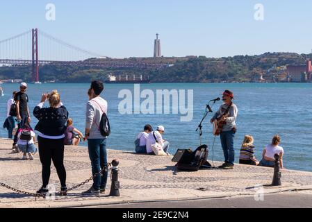 Portugal, Lissabon, 08. Oktober 2018: Straßenmusiker spielt E-Gitarre am Wasser. Vor dem Musiker gibt es Noten und ein Mikrofon. Stockfoto