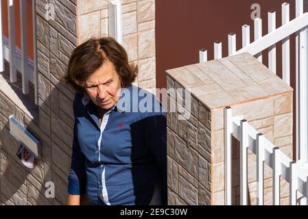 Portugal, Lissabon, 09. oktober 2018: Eine ältere Einheimische blickt vom Tor ihres Hauses auf die Straße. Stockfoto