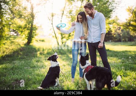 Junge glückliche Paar mit Hunden spielen, Spaß im Park Stockfoto