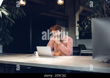 Verwirrt nachdenklichen Geschäftsmann sitzt an seinem Arbeitstisch in einem Büro Stockfoto