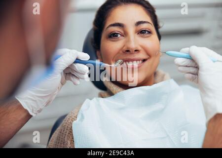 Lächelnde Frau, die ihre Zähne vom Zahnarzt überprüft. Frau mit zahnärztlichen Untersuchung in der Klinik. Stockfoto