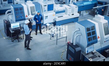 Industrie vier Fabrik: Weibliche Führungskraft und Chief Engineer Inspect Facility Workshop, Blick auf Roboterarm arbeiten an der Montagelinie, sprechen Sie mit Arbeiter. Hoch Stockfoto