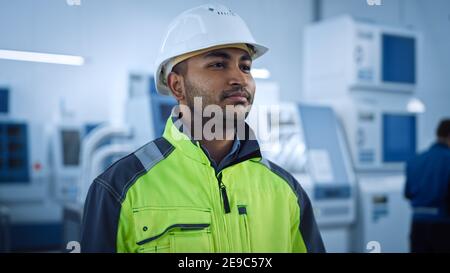 Industrie 4 Fabrik: Portrait eines modernen Arbeiters Tragen von Sicherheitsjacke und Harthut Spaziergänge durch Zeitgenössische Industrie-Workshop, wo Profis Stockfoto