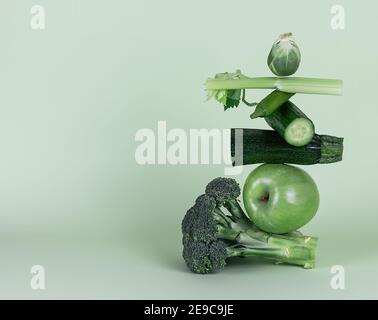 Frisches grünes Gemüse und Obst auf grünem Hintergrund. Gleichgewicht schwimmende Lebensmittelbalance. Stockfoto