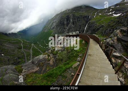 Ein Blick auf die Straße voller Haarnadeln bei Trollstigen – der Troll-Straße in Norwegen. Der Sturm kommt aus dem Tal. Stockfoto