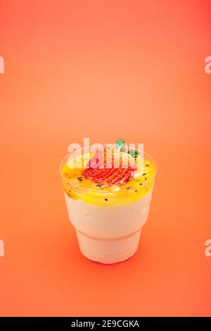 Süßes Dessert im Glas mit Keks, Erdbeeren und Schlagsahne. Leerer Raum für Text. Auf orangefarbenem Hintergrund Stockfoto