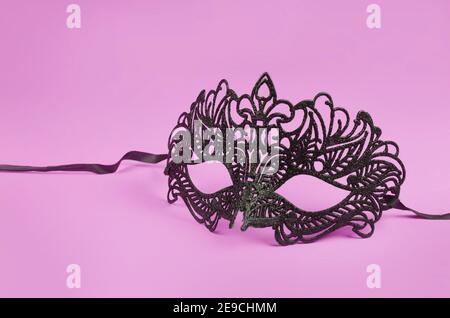 Venezianische schwarze Maske auf rosa Hintergrund Stockfoto