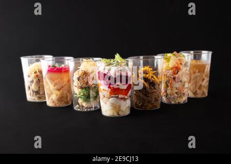Verschiedene Salate und Snacks in Plastikbechern, Studiofoto. Catering, Lieferung von Lebensmitteln. Stockfoto