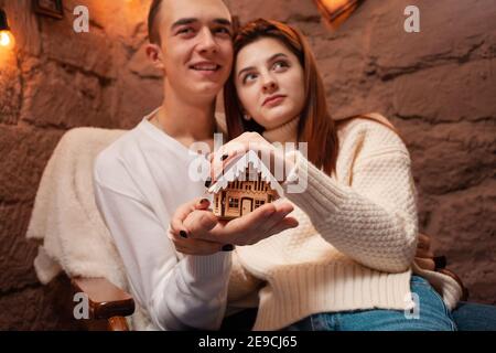 Eine junge Familie träumt von ihrem eigenen Zuhause, Hypothek, Darlehen. Ein Mädchen und ein Kerl in einem Neujahrsfotostudio. Weihnachtsträume. Junge Menschen halten ein h an Stockfoto