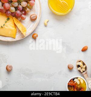 Weinkomposition auf hellgrauem rustikalem Betonhintergrund. Rahmen aus rosa Rosé Wein Flasche Käse Nüsse und Trauben Honig. Camembert Käse, Wein Stockfoto