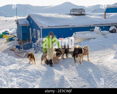 Zurück von der Jagd. Der Jäger trägt traditionelle Hosen und Stiefel aus Eisbärpelz. Die traditionelle und abgelegene grönländische inuit Villa Stockfoto