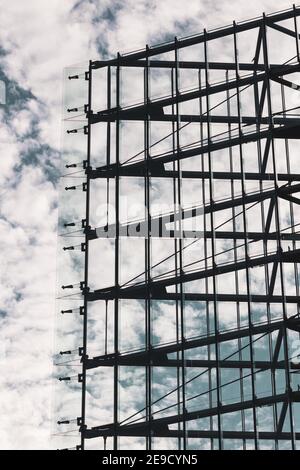 Moderne symmetrische Architektur, alle Glas-und Stahlfassade Dreieck mit einem blauen und Wolkenhimmel im Hintergrund geformt Stockfoto