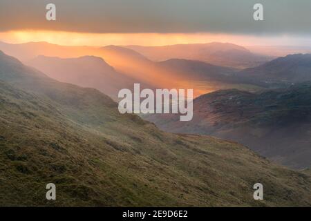 Goldenes Abendlicht bei Sonnenuntergang bricht durch Wolken auf Berge. Eskdale Valley im englischen Lake District. Stockfoto