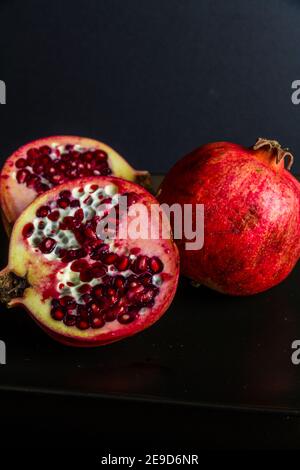 Drei Granatäpfel in dunkler Umgebung, Nahaufnahme, Makro, Porträt. Stockfoto