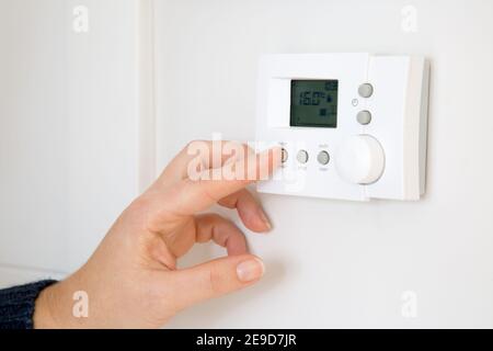 Frau Hand Einstellung digitale Zentralheizung Thermostat zu Hause Stockfoto