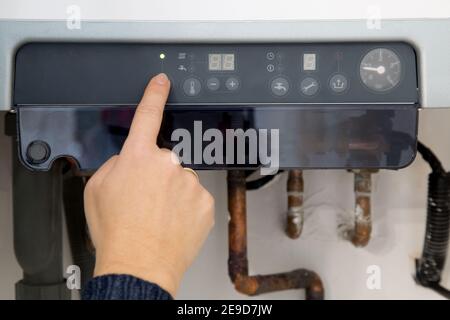 Frau Hand Schalten auf den Heizkessel zu Hause Stockfoto