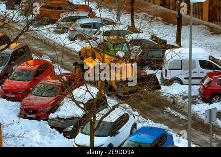 Madrid, Spanien - 10. Januar 2021: Autos im Schnee geparkt und Schneepflüge Lichtung der Straße während eines historischen Schneefalls in Madrid , am 10. Januar 2021 Stockfoto