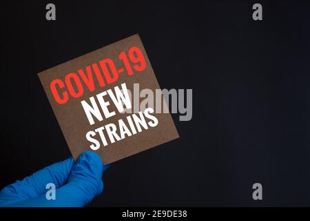 Covid-19 neue Sorten. Hand in blauem Handschuh. Schwarzer Hintergrund. Mutiertes Coronavirus-Konzept. Stockfoto