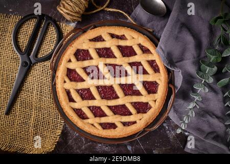 Draufsicht auf hausgemachten Kuchen namens "Linzer Torte", ein traditionelles österreichisches Shortcake-Gebäck mit Obstkonserven und in Scheiben geschnittenen Nüssen mit Gitterdessig gekrönt Stockfoto