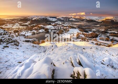 Blick von Loughrigg fiel an einem Wintermorgen mit goldenem Licht Baden die schneebedeckte Landschaft. Lake District, Großbritannien. Stockfoto