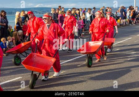 Die Red Barrows, ein Take on the Red Arrows, schieben ihre Schubkarren, die im August am Weymouth Carnival in Weymouth, Dorset UK teilnehmen Stockfoto