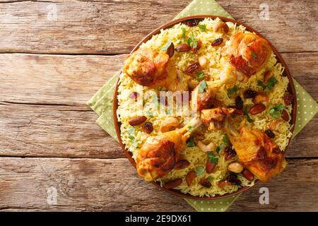 Hausgemachter arabischer gewürzter Reis und Huhn mit Nüssen, Rosinen in der Nähe in der Platte auf dem Tisch. Horizontale Ansicht von oben Stockfoto