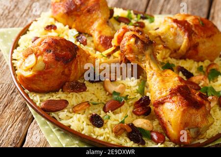 Arabisches Huhn Majboos, die ein gewürzter Reis und Huhn mit Nüssen gekrönt ist, Rosinen in der Nähe in der Platte auf dem Tisch. Horizontal Stockfoto