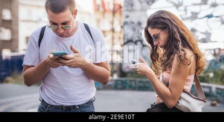 Junges Paar mit Smartphones zusammen. Menschen, die neue Technologietrends verfolgen. Jugend, neue Generation Internet Freundschaft Konzept. Emotionale isola Stockfoto