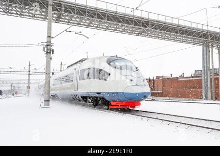 Der Hochgeschwindigkeitszug nähert sich im Winter dem Bahnsteig an Tag Schneesturm Stockfoto