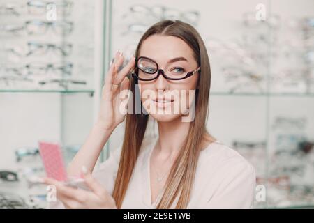 Junge schöne Modell Frau mit Brille für Make-up in Optiker. Lächelnde Frau in einer Brille zum Schminke Stockfoto