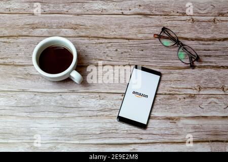 Ein Mobiltelefon oder Mobiltelefon auf einem Tisch Oder Schreibtisch mit der Amazon Shopping App geöffnet und ein Kaffee daneben Stockfoto