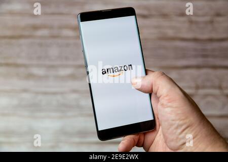 Eine Hand, die ein Mobiltelefon oder Mobiltelefon mit hält Die Amazon Shopping App auf dem Bildschirm Stockfoto