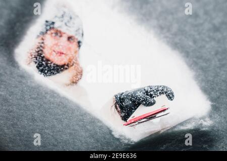 Frau entfernt Eis von der Windschutzscheibe - Reinigung gefrorenen Auto Stockfoto